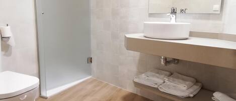 A modern bathroom with a toilet, a sink, and a shower.