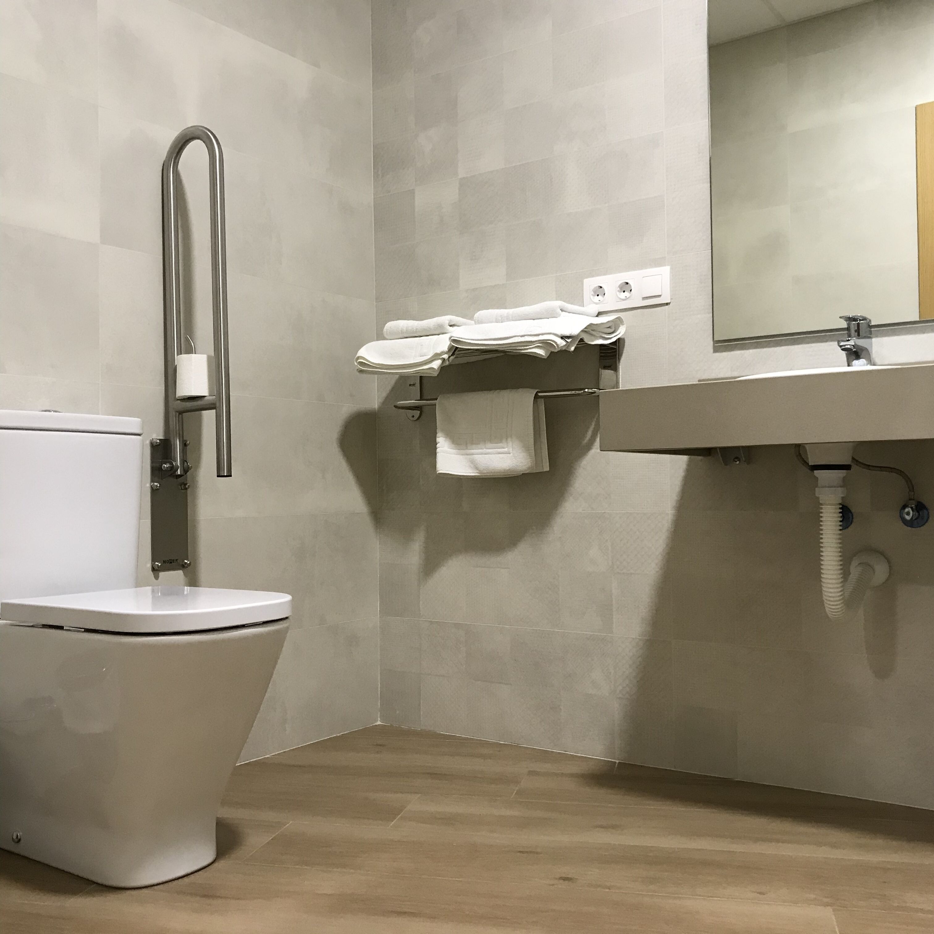 A modern bathroom with a toilet, a sink, and a mirror.