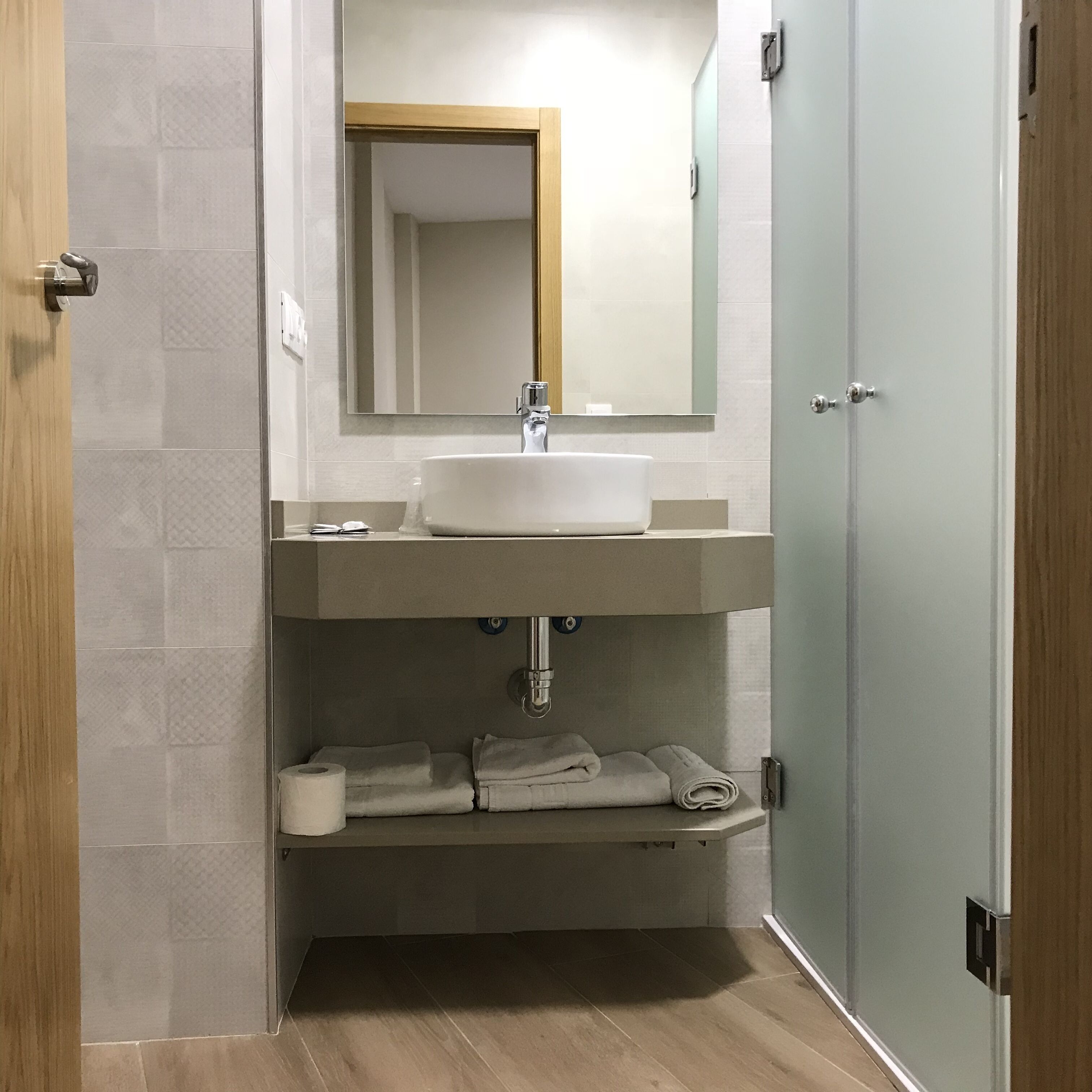 A bathroom with a white sink, a mirror, and a towel rack.