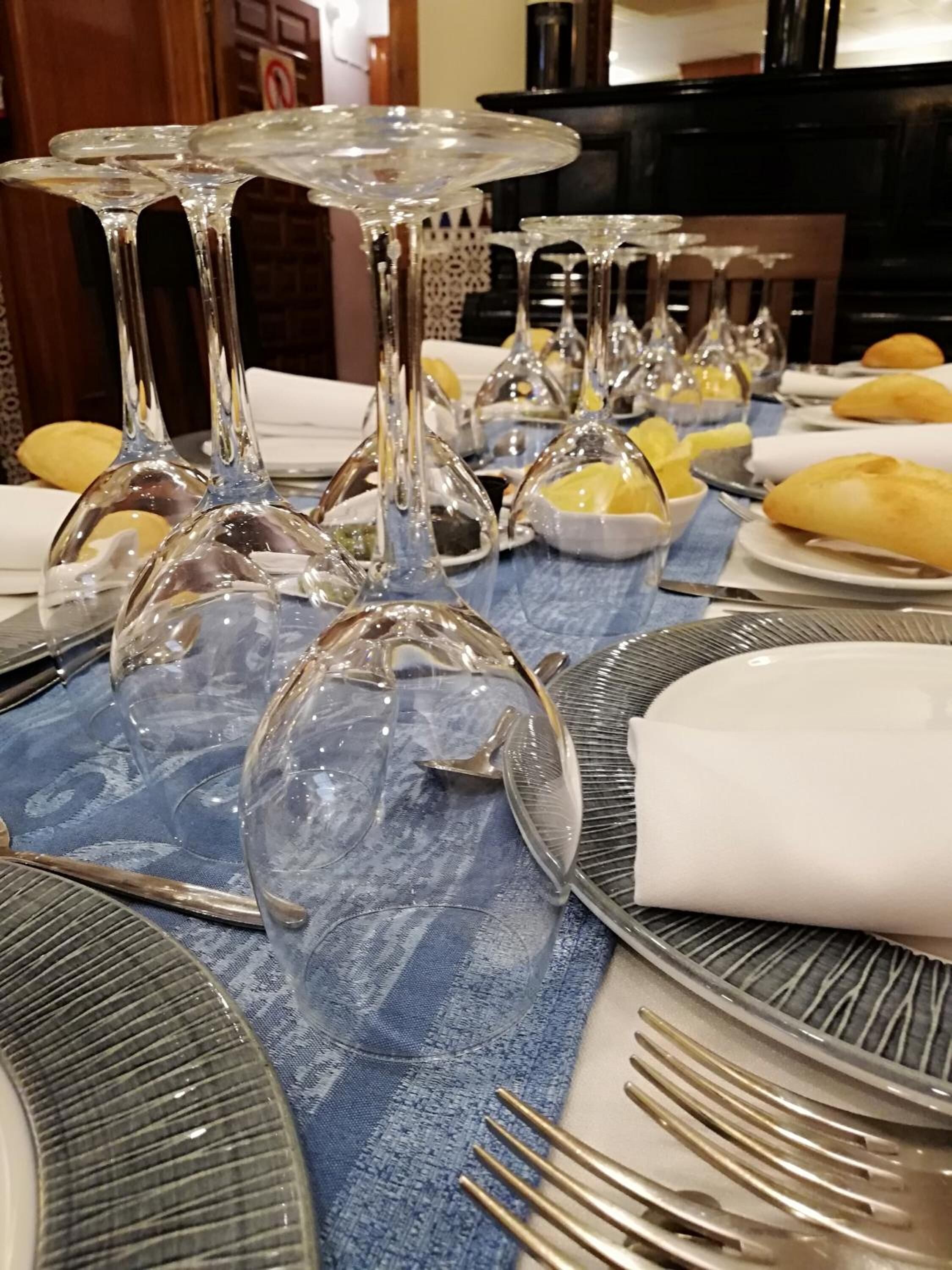 A table set with clear glass wine glasses, plates, and cutlery.