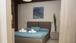 Quarto moderno com uma cama grande, uma mesa de cabeceira, uma luminária pendente e um quadro na parede.