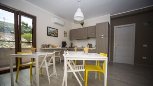 Cozinha moderna com armários brancos, bancada clara e luminária suspensa.
