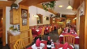 A restaurant with wooden interiors, red tablecloths, and wine glasses set for dining. - Albergo Nido Verde (Lavarone)