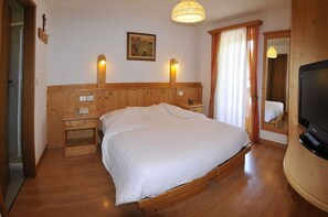 A wooden-framed bedroom with a bed, bedside tables, a TV, and a painting on the wall. - Albergo Nido Verde (Lavarone)
