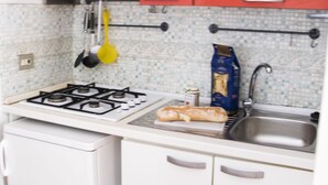Uma cozinha compacta com fogão a gás, pia e armários vermelhos.