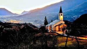 A church with a bell tower, surrounded by mountains and a valley. - Relais des Alpes (Giaglione)