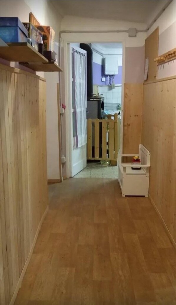 Un estrecho pasillo con piso de madera que conduce a una zona de cocina con un lavamanos y armarios.