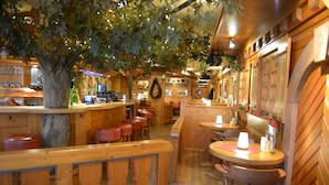 En mysig restaurang med träinredning, en bardisk och olika typer av sittplatser.