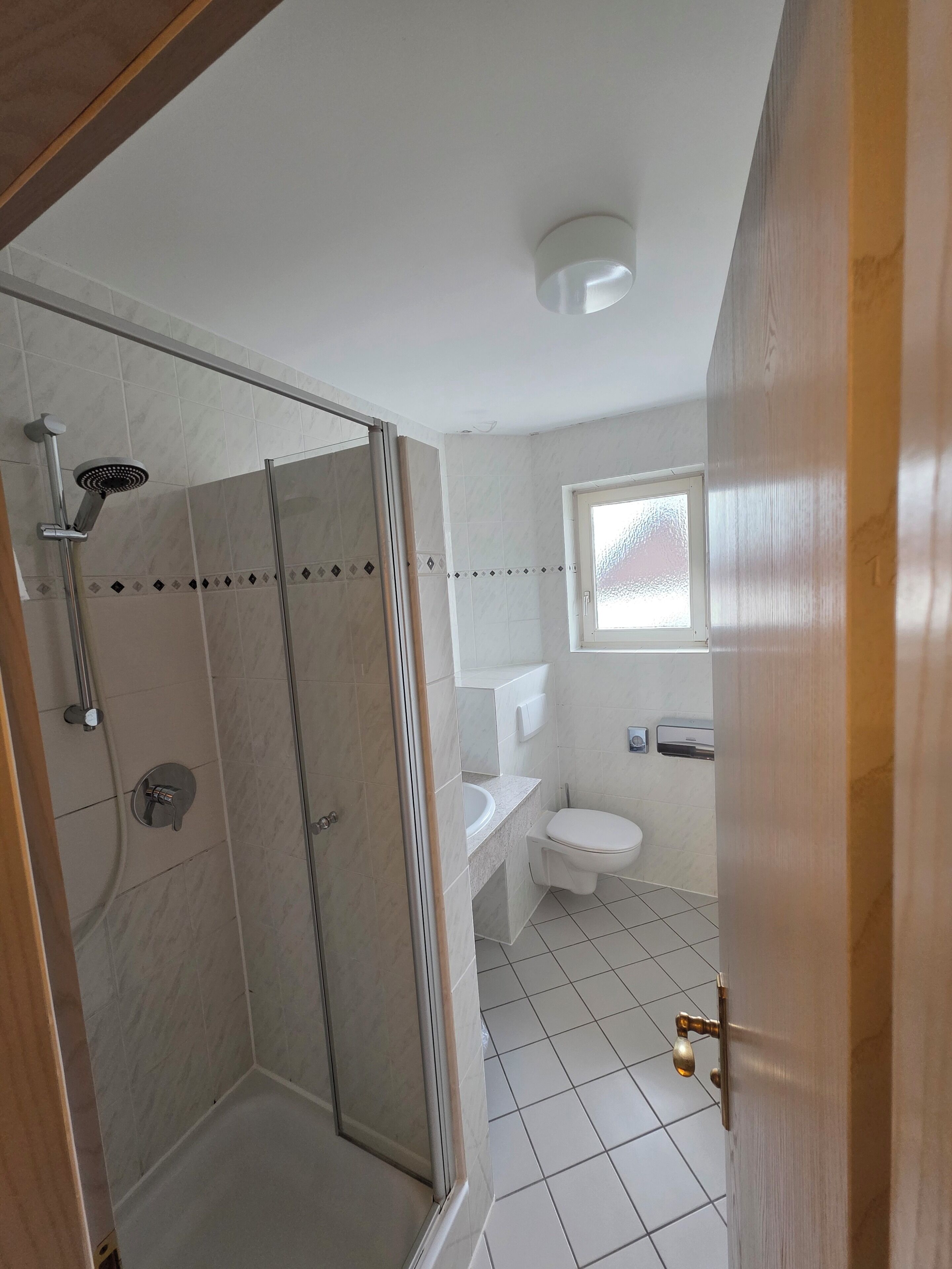 Baño con ducha, inodoro, lavabo y ventana.