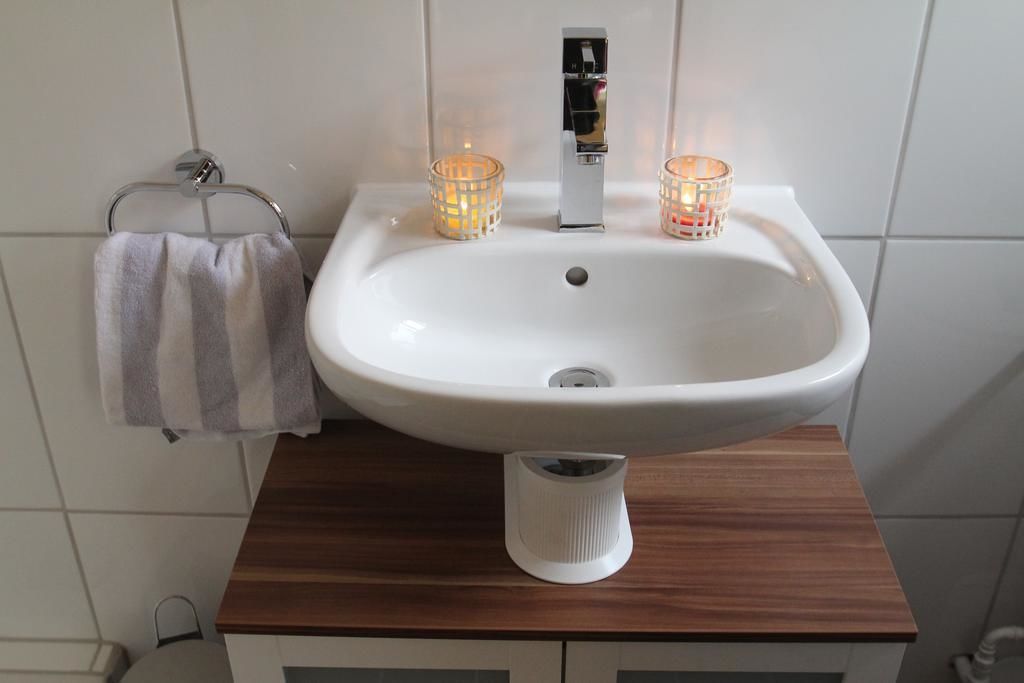 Ein Badezimmer mit einem weißen Waschbecken, zwei brennenden Kerzen und einem Handtuch an einem Haken.
