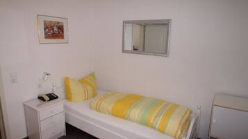 A bedroom with a bed, a nightstand, a mirror, and a framed picture on the wall.
