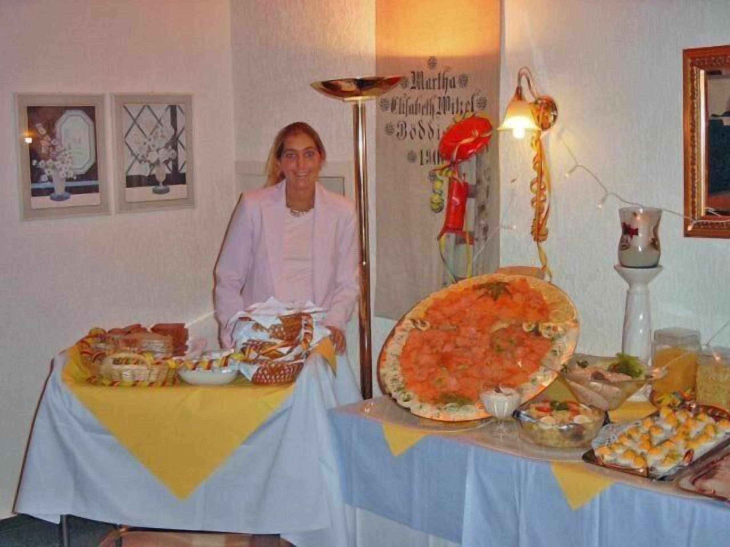 A room with a table set for a meal, featuring a large pizza and various dishes.
