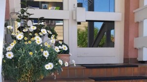 A set of outdoor steps leading to a building entrance with a potted plant and flowers in the foreground. - Hotel Irene (Bad Konig)