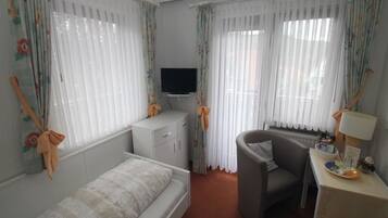 A bedroom with a bed, a desk, a chair, and a television.