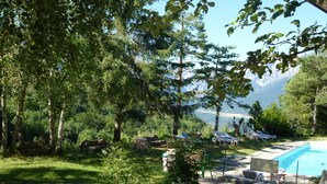 Zona de piscina con sillones de descanso y vistas a montañas.