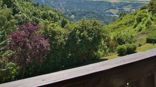 Paisaje montañoso con una terraza de madera al frente.