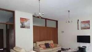 Un salon avec un canapé, un téléviseur et un lustre.
