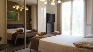 A hotel room with two beds, a large mirror, a flat-screen TV, and a chandelier. - B&B Il Melograno (Formigine)