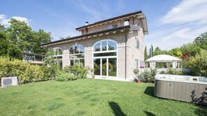 A two-story house with a large lawn, a hot tub, and a covered patio area. - B&B Il Melograno (Formigine)