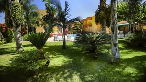 A well-maintained garden with palm trees and a pool area in the background. - Camyuva Motel (Kemer)