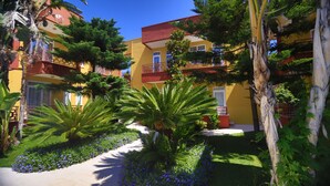 A multi-story building with balconies, surrounded by lush greenery and flowering plants. - Camyuva Motel (Kemer)