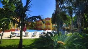 A pool area with lounge chairs and a building with balconies in the background. - Camyuva Motel (Kemer)