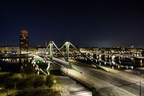 Un paisaje urbano nocturno con un puente destacado, un río y edificios iluminados.