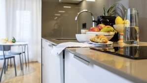 A modern kitchen with a countertop, a bowl of fruit, a croissant, and a water bottle. - THE FLAG Oskar M. (Frankfurt)