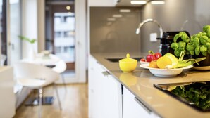 A modern kitchen with a stainless steel sink, a yellow bowl, fresh vegetables, and a white chair. - THE FLAG Oskar M. (Frankfurt)