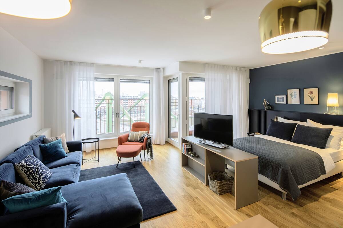 Ein modernes Hotelzimmer mit einem großen Bett, einem Fernseher, einer Couch und einem Sessel.