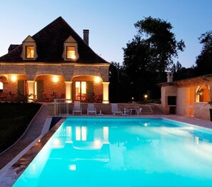 A large house with a swimming pool, stone walls, and a well-lit entrance. - Hôtel Bon Encontre (Sarlat-la-Canéda)