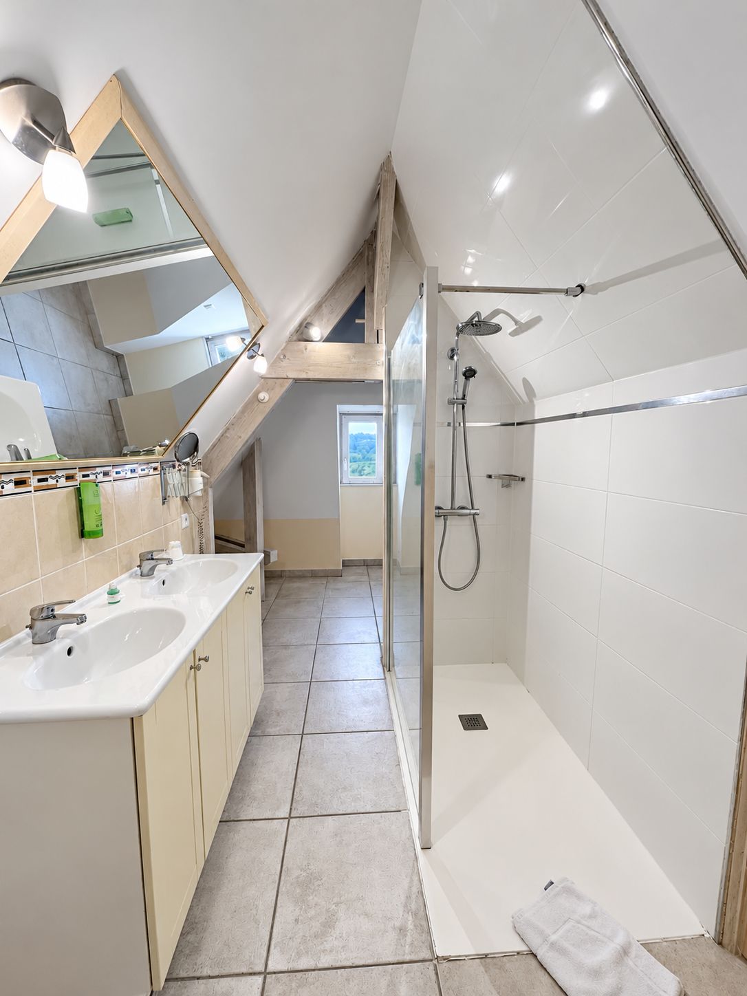 A modern bathroom with two sinks, a shower, and a glass-enclosed shower area.
