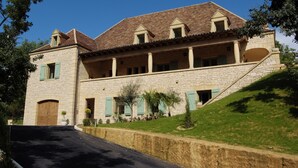 A large stone building with a sloped roof, multiple windows, and a central courtyard.
