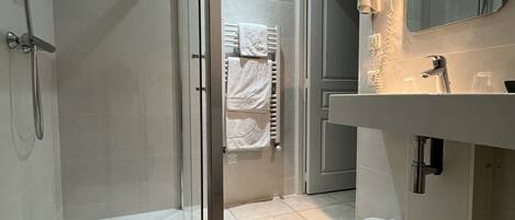 A modern bathroom with a glass-enclosed shower, a toilet, and a sink with a mirror.