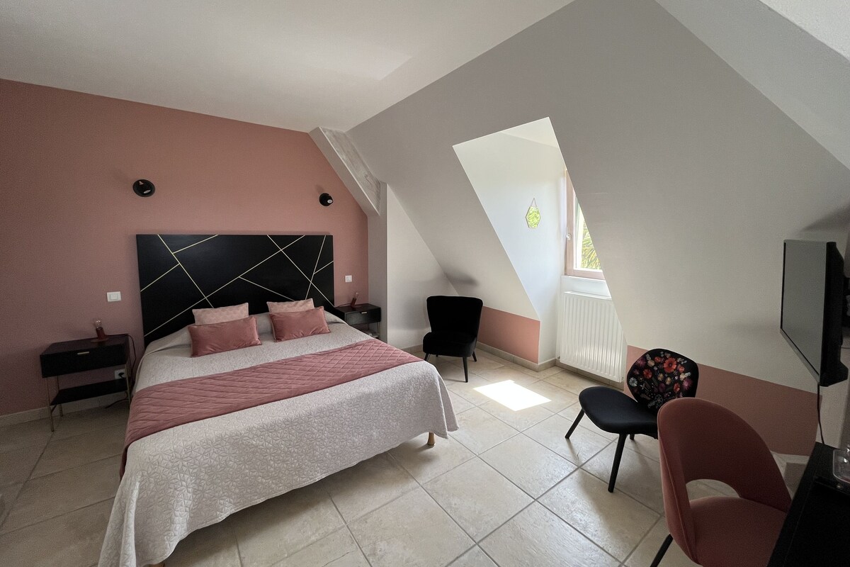 A bedroom with a bed, a chair, a desk, and a TV.