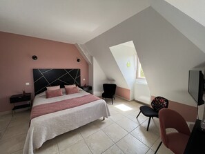 A bedroom with a bed, a chair, a desk, and a TV. - Hôtel Bon Encontre (Sarlat-la-Canéda)