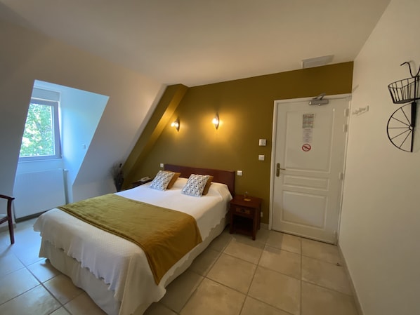 Quarto com cama, mesa de cabeceira, porta e janela.