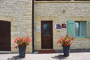 Un edificio de piedra con un letrero de recepción, un letrero de hotel y dos macetas con flores rojas.