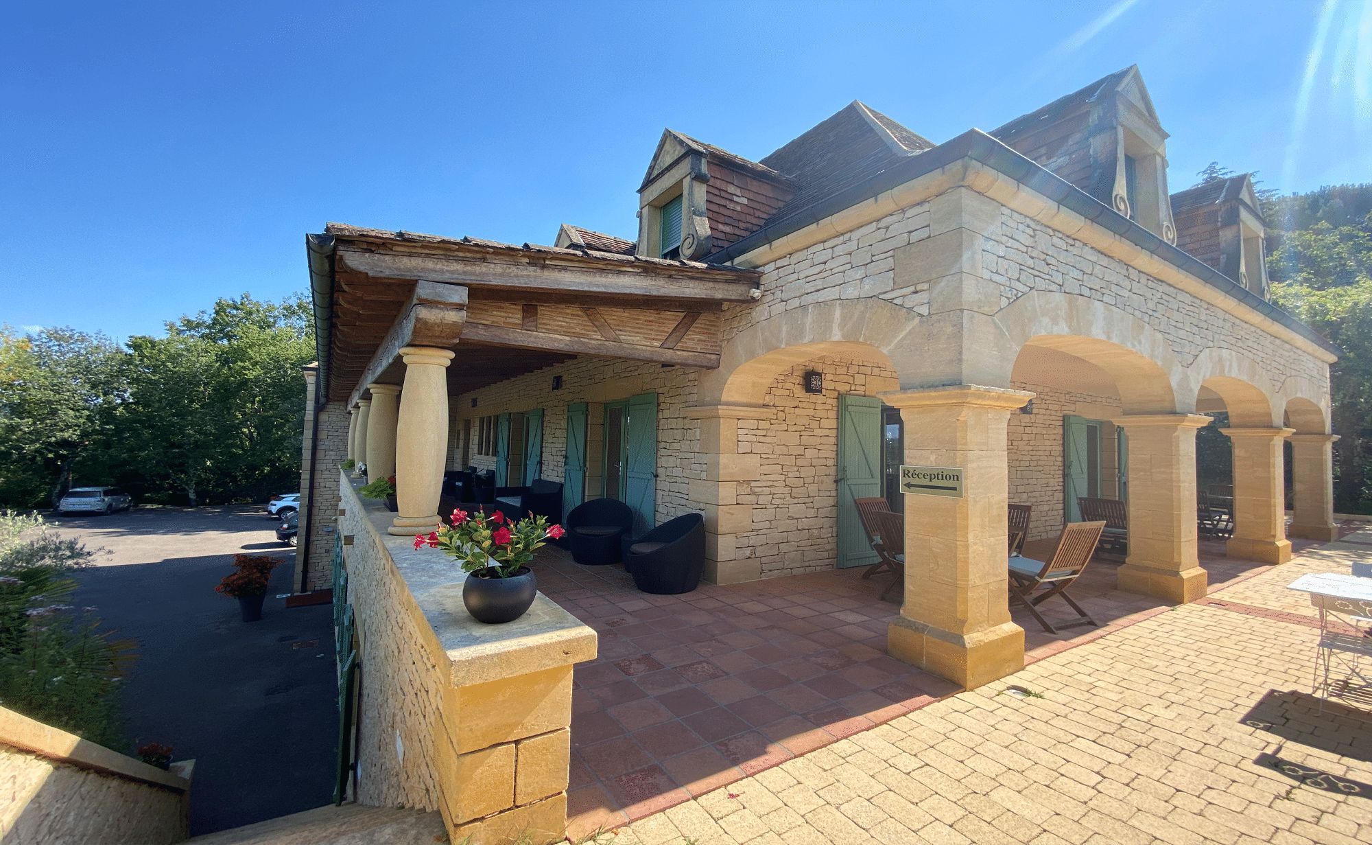A stone building with a reception area, outdoor seating, and a paved entrance.