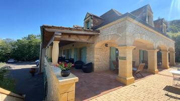 A stone building with a reception area, outdoor seating, and a paved entrance.