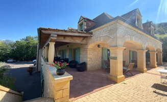 Un edificio de piedra con recepción, asientos exteriores y entrada pavimentada.