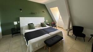 A bedroom with a bed, a bench, a chair, a nightstand, and a wall-mounted light fixture.