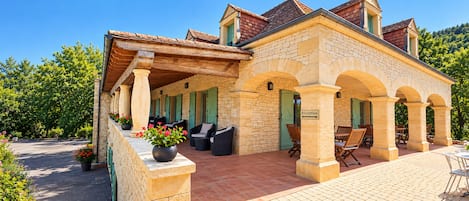 A stone building with a covered patio area, outdoor seating, and a reception sign.