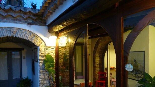 A courtyard with stone arches, a dining area with chairs, and potted plants. - B&B Amphisya (Roccella Jonica)