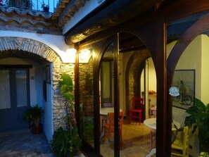 A courtyard with stone arches, a dining area with chairs, and potted plants. - B&B Amphisya (Roccella Jonica)