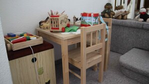 Una mesa de madera con juguetes y un pequeño armario de madera.