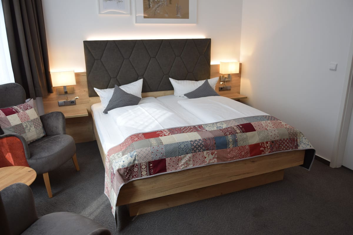A hotel room with a large bed, two bedside tables, a chair, and a nightstand.