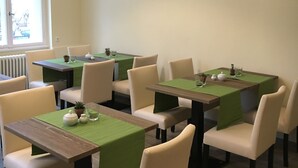 Un comedor con mesas y sillas, una lámpara colgante y un ventanal con vistas.