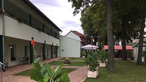 A courtyard with a brick pathway, outdoor seating, and potted plants. - Hotel Bergschlösschen (Jueterbog)