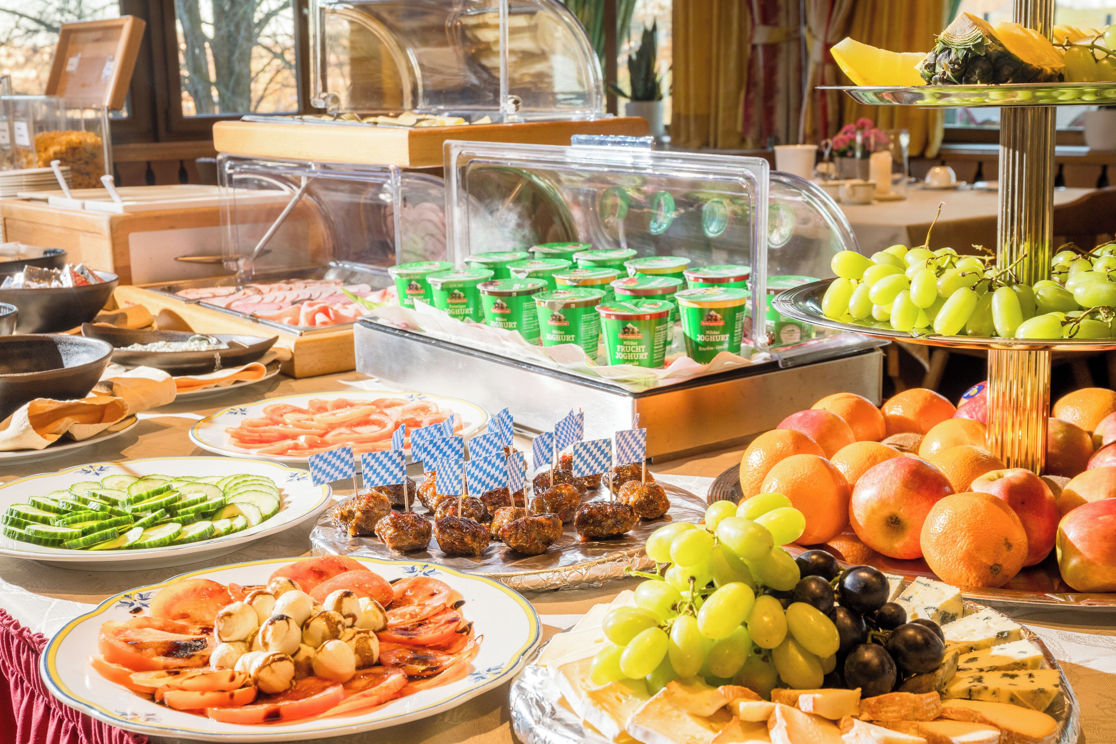 A buffet with various food items including fruits, cheeses, and meatballs.